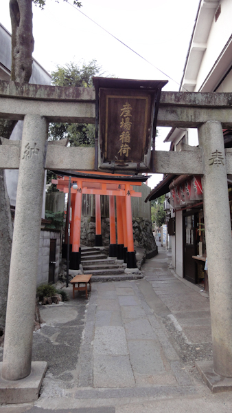 a view through a stone torii to several vermillan wooden ones